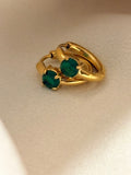 18kt gold plated earrings with emerald stones on a beige background
