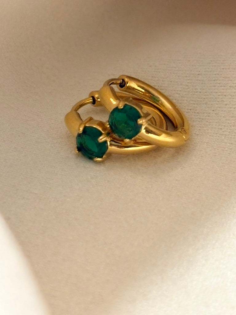 18kt gold plated earrings with emerald stones on a beige background