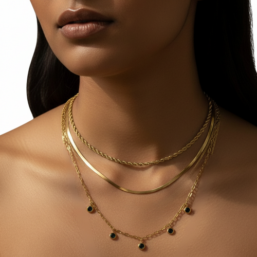 Close-up of a woman wearing gold necklaces with a neutral background