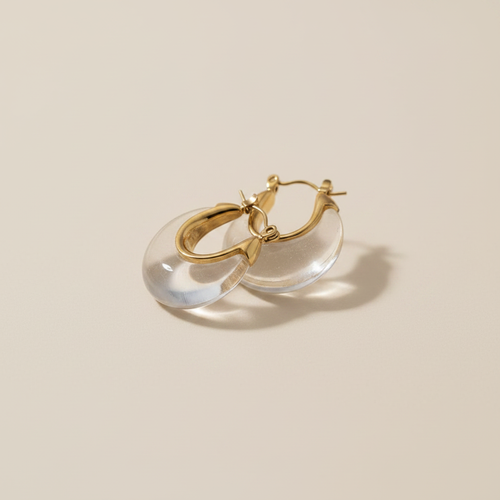 Gold hoop earrings with clear stones on a soft fabric background