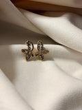 Flower-shaped earrings with zirconia stones on a soft white fabric background
