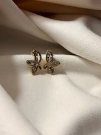 Flower-shaped earrings with zirconia stones on a soft white fabric background