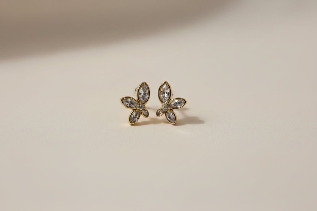 Flower-shaped earrings with zirconia stones on a soft white fabric background