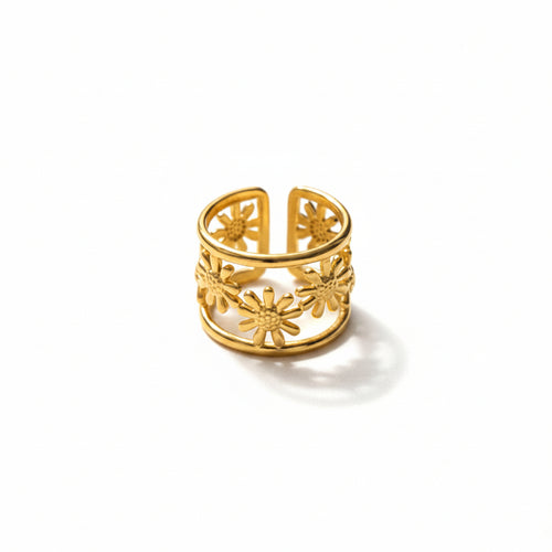 Gold ring with intricate design on a light gray surface