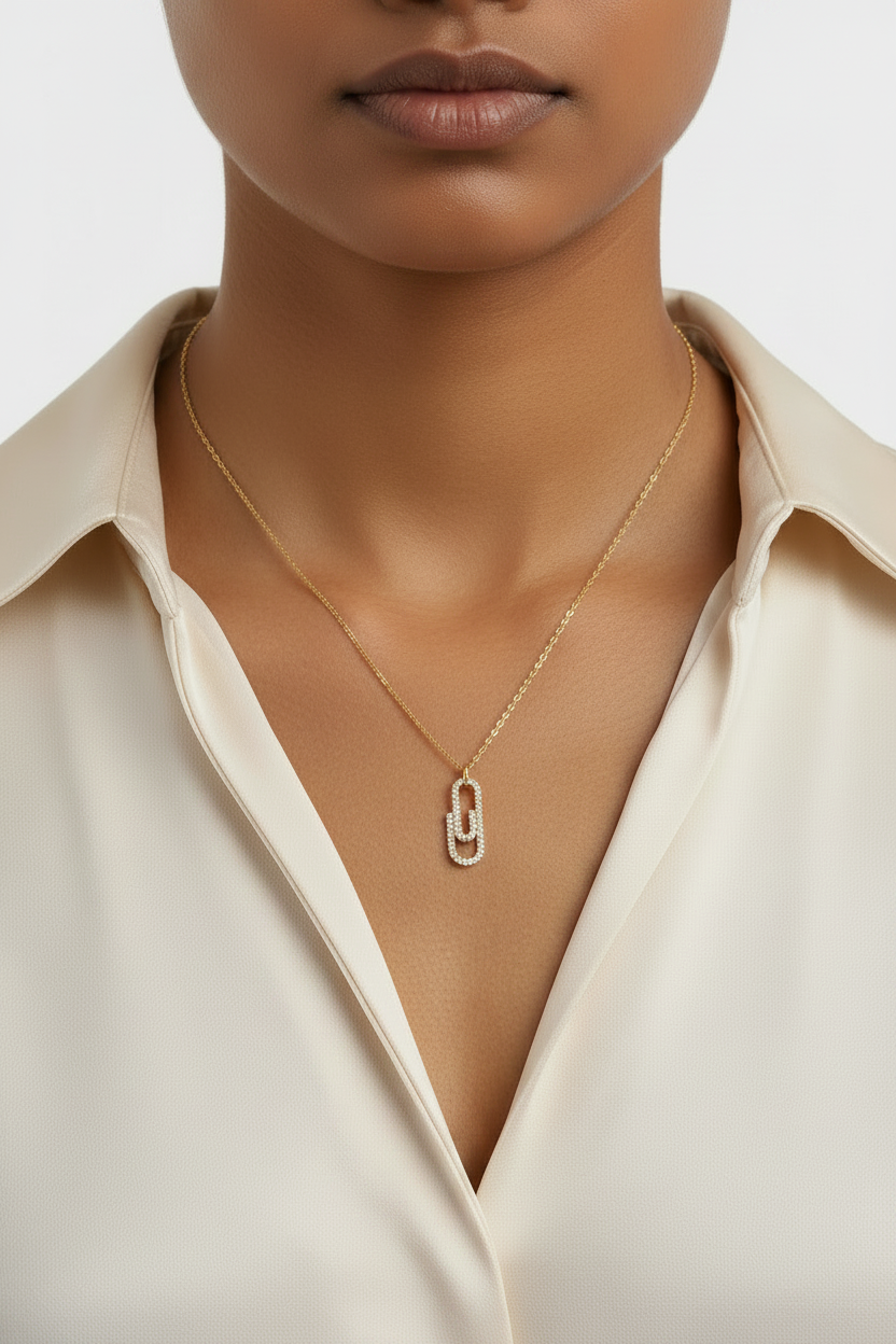 A woman wearing a gold necklace with interlocking AAA cubic zirconia link pendant in 18KT PVD gold-plated stainless steel by NIYANSA.
