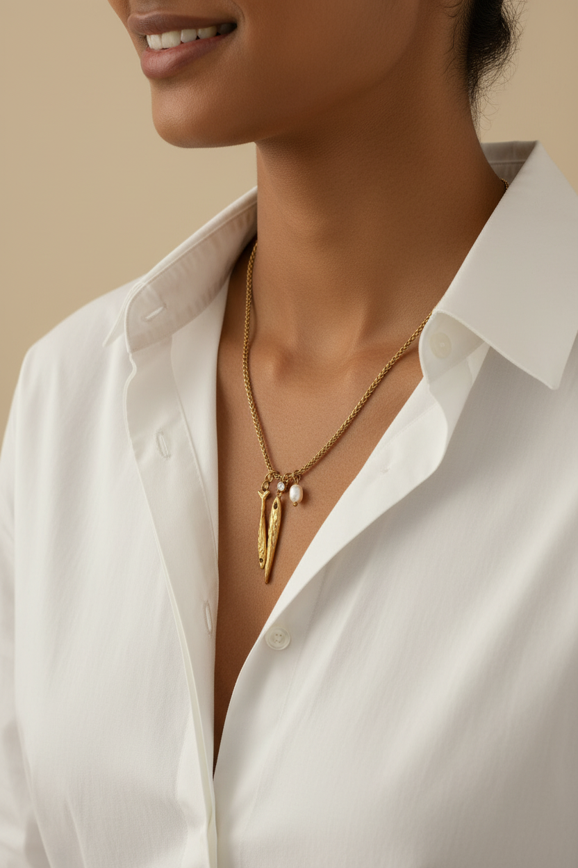 Woman wearing the NIYANSA Ocean Muse Long Necklace fish pendants with a freshwater pearl charm and AAA cubic zirconia accent on a textured gold chain.