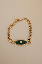 18kt pvd plated gold bracelet with a green stone in the center.