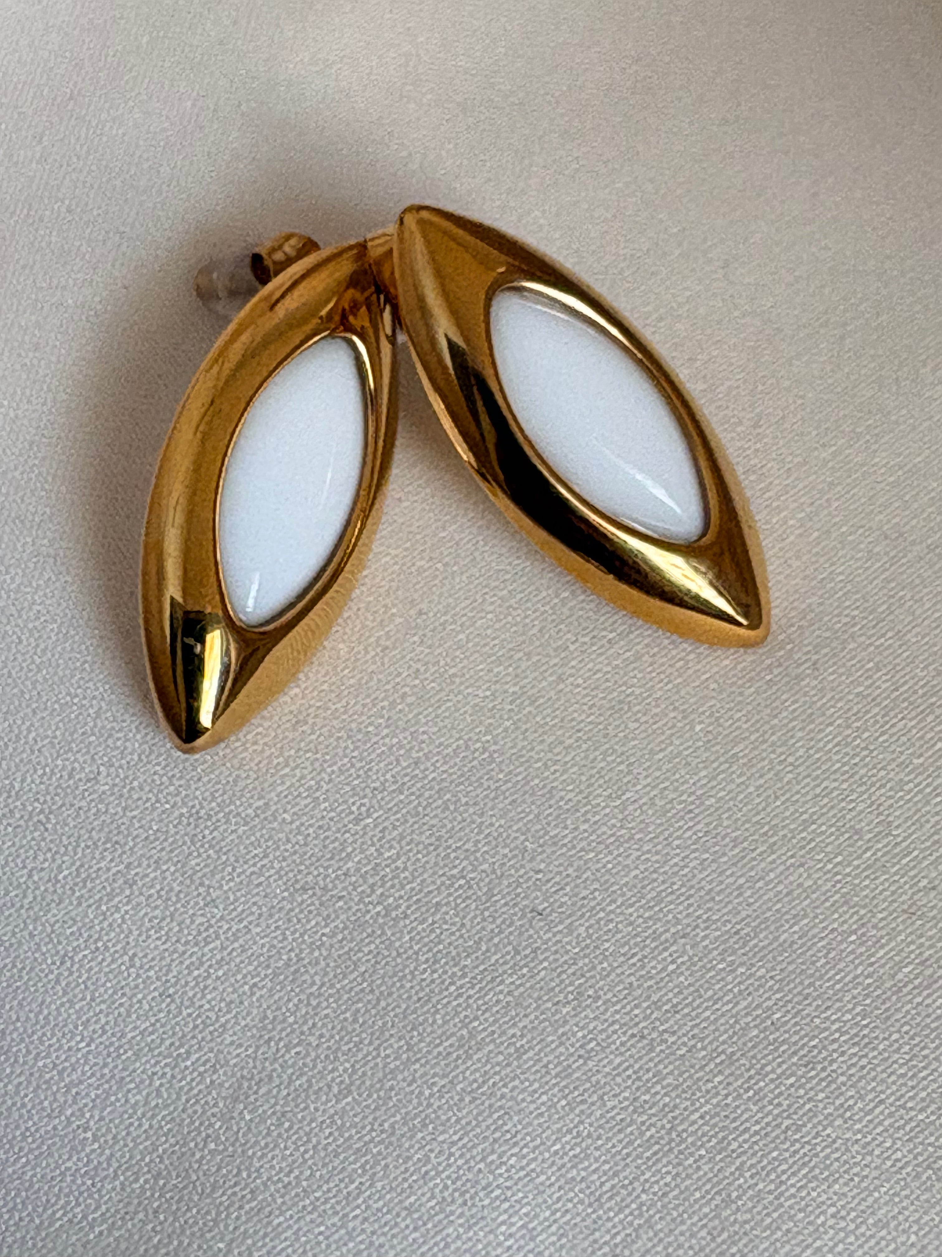Marquise-shaped gold stud earrings with white enamel detailing by NIYANSA.