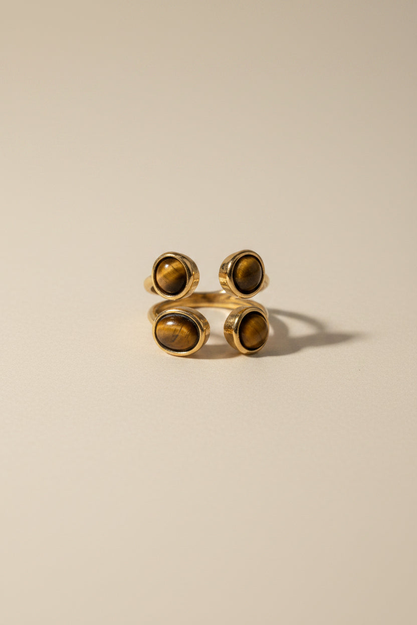 Gold cufflinks with dark stones on a textured beige surface