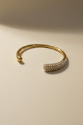 Gold bracelet with pearl-like beads on a light beige background