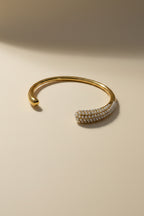 Gold bracelet with pearl-like beads on a light beige background