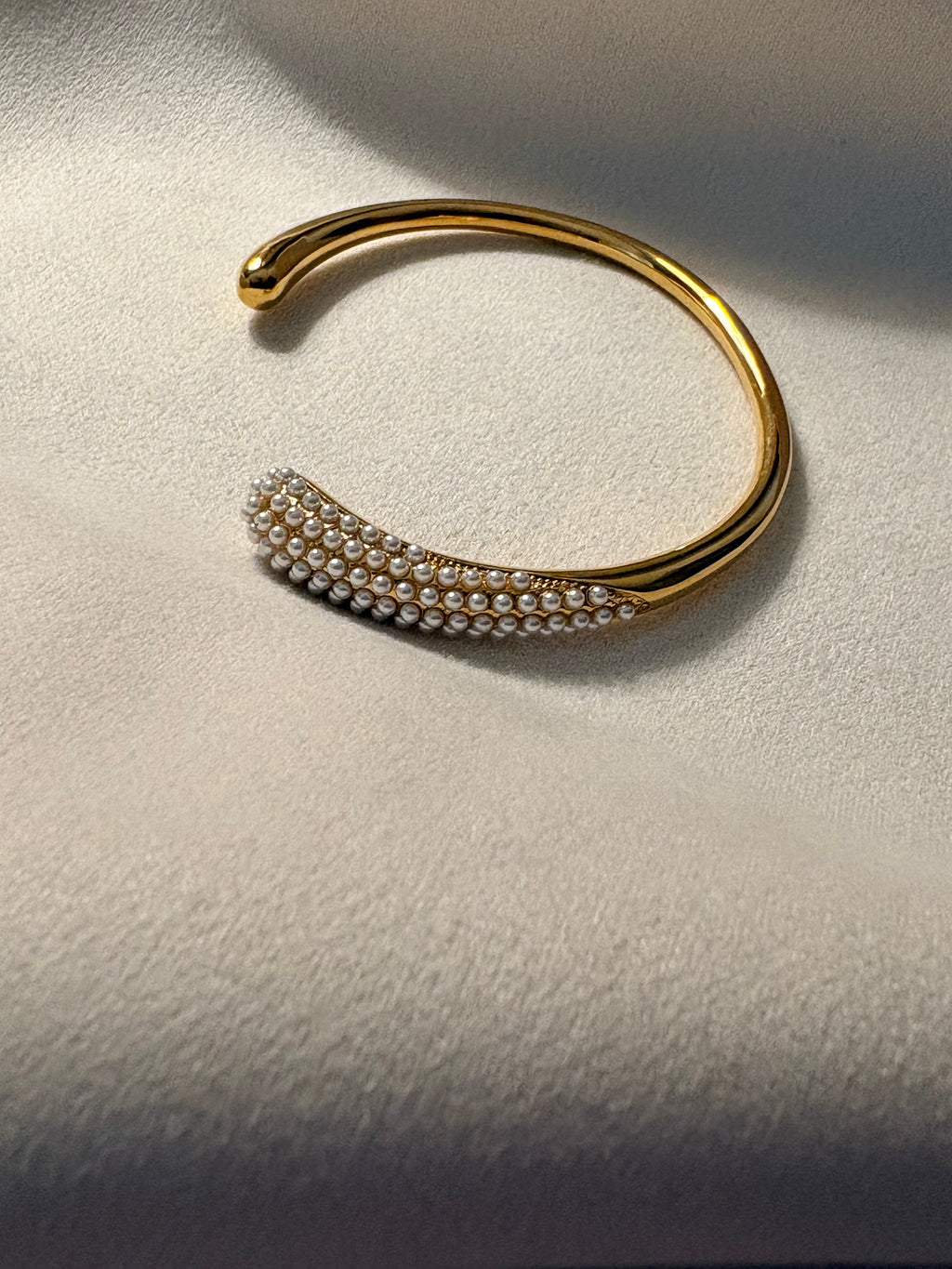 Gold bracelet with pearl-like beads on a textured surface