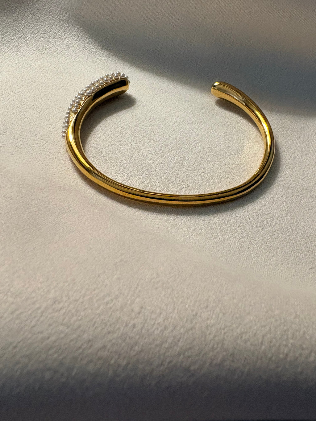Gold bracelet with a textured finish on a light beige background
