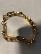 Gold chain bracelet on a light beige background