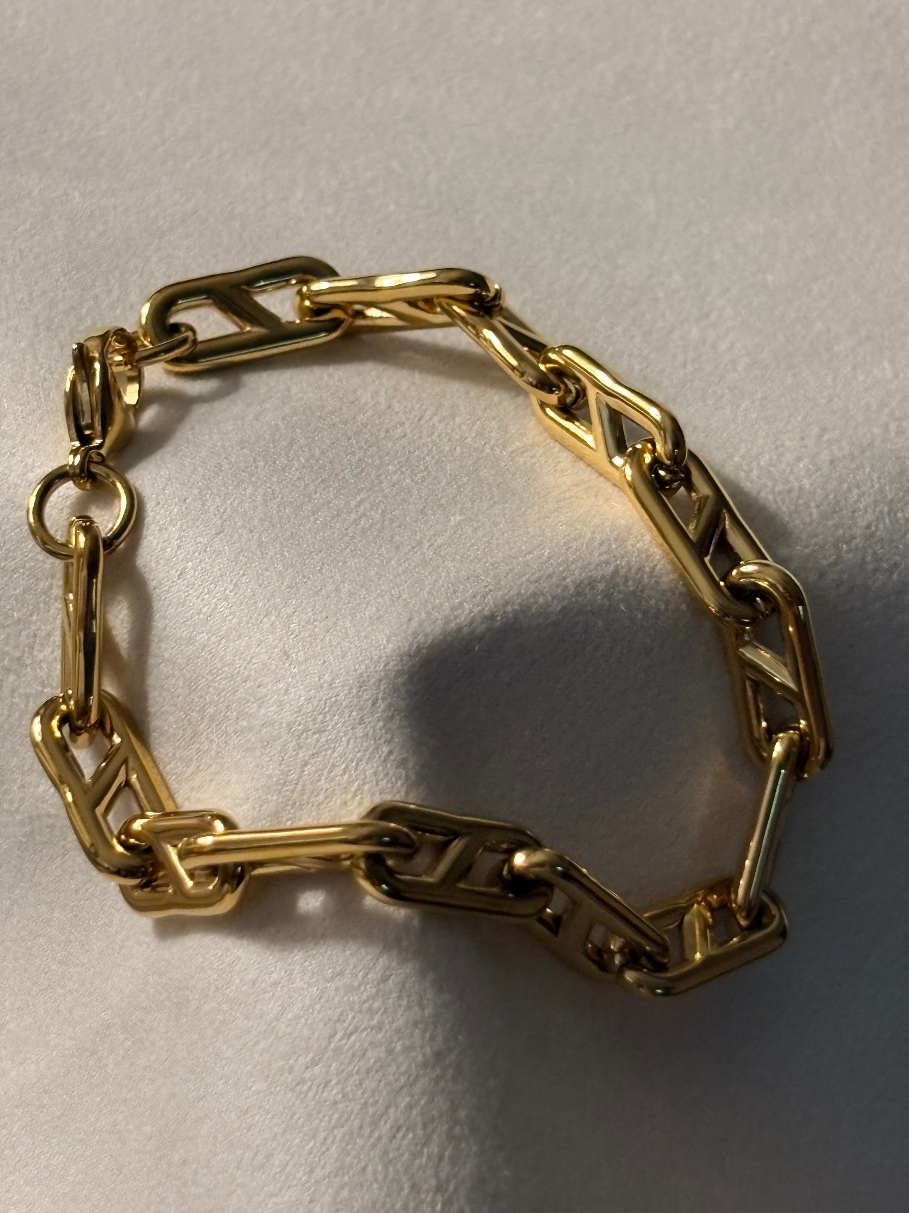 Gold chain bracelet on a light beige background