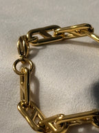 Gold chain bracelet on a light beige background