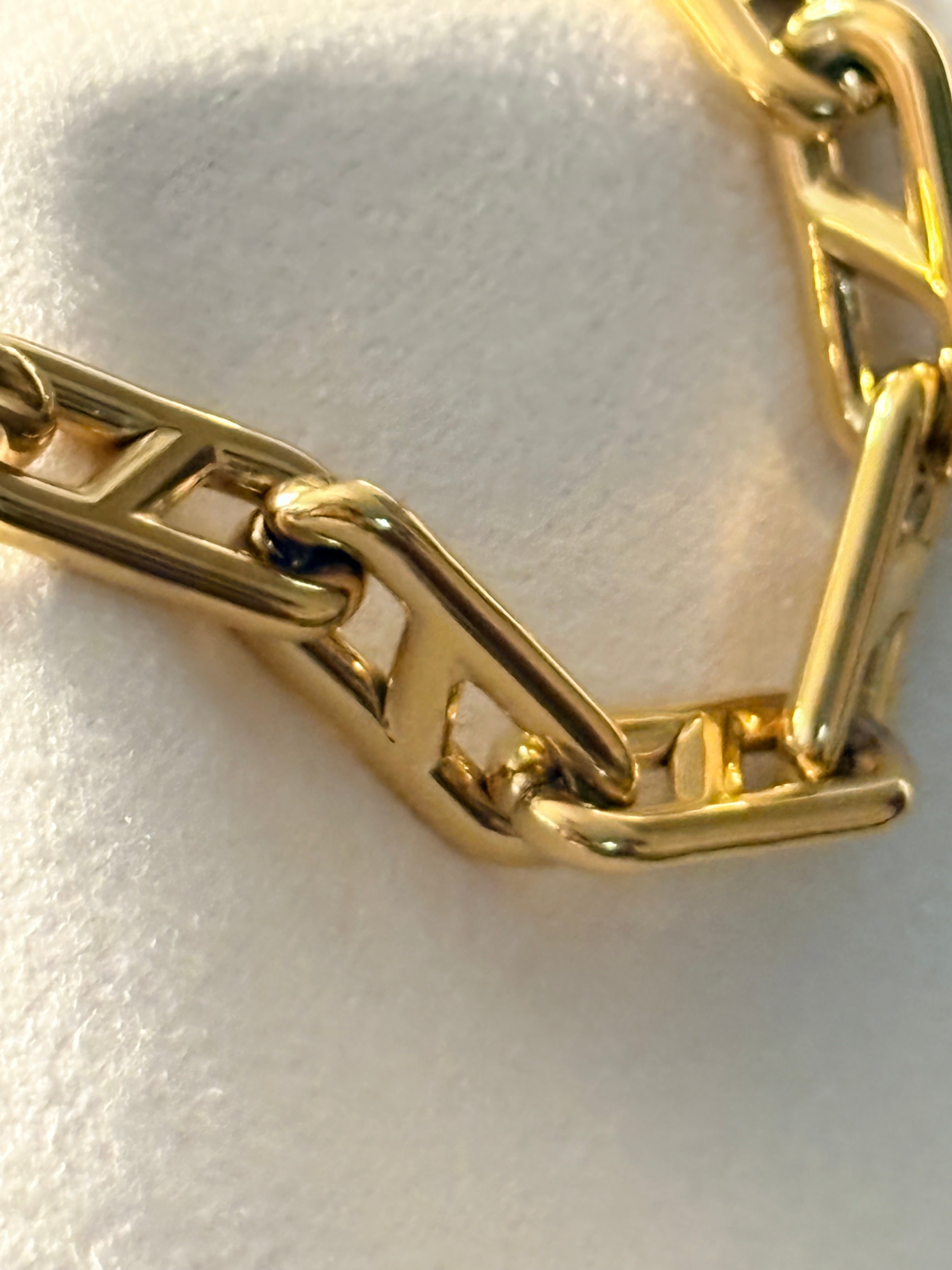 Gold chain bracelet on a light fabric background