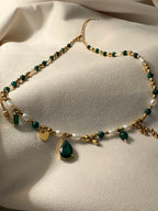 Necklace with green and gold beads on a light beige fabric background