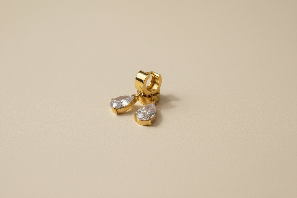 Gold hoop earrings with AAA grade CZ stones on a beige background.