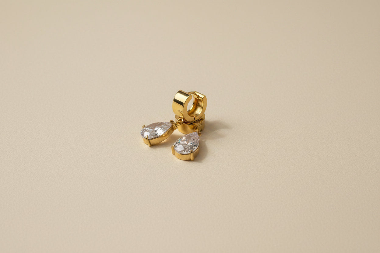 Gold hoop earrings with AAA grade CZ stones on a beige background.