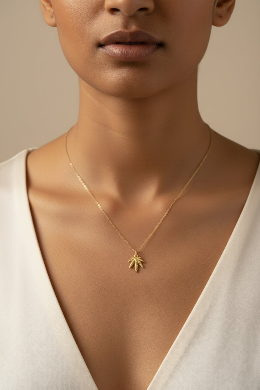 Gold charm shaped like a palm tree on a light beige background