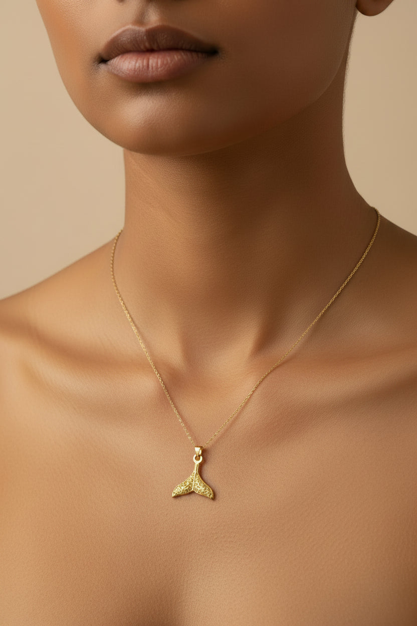 Whale Fin Charm on a thin gold chain crafted in 18kt gold plated on 316L grade titanium steel.
