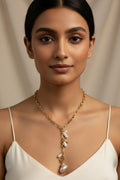 Woman wearing a gold necklace with pearls against a beige background