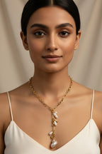Woman wearing a gold necklace with pearls against a beige background