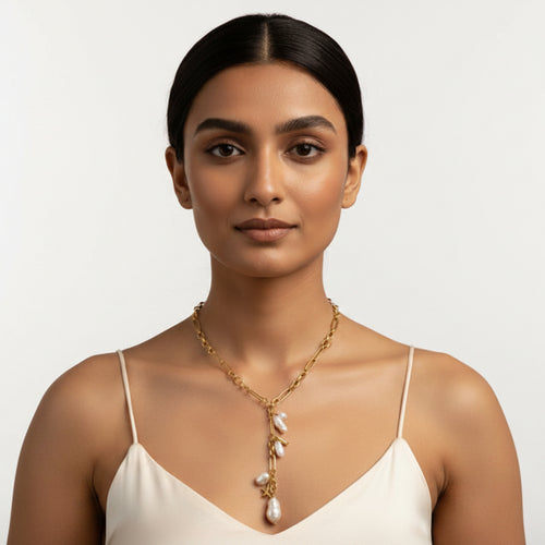 Woman wearing a gold necklace with pearls against a beige background