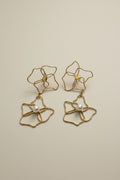 Gold floral earrings with pearl centers on a light gray background