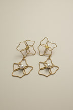 Gold floral earrings with pearl centers on a light gray background