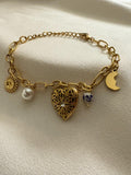 18kt pvd gold plated bracelet with various charms on a light background.