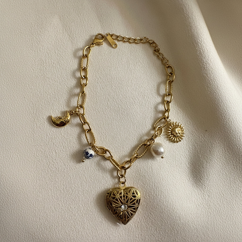 18kt pvd Gold bracelet with heart-shaped charm and various other charms on a beige background