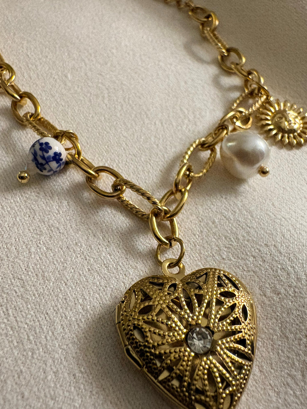 18kt gold chain bracelet with heart-shaped locket and decorative beads on a light background