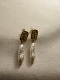 Pair of 18kt gold plated freshwater pearl earrings on a beige surface